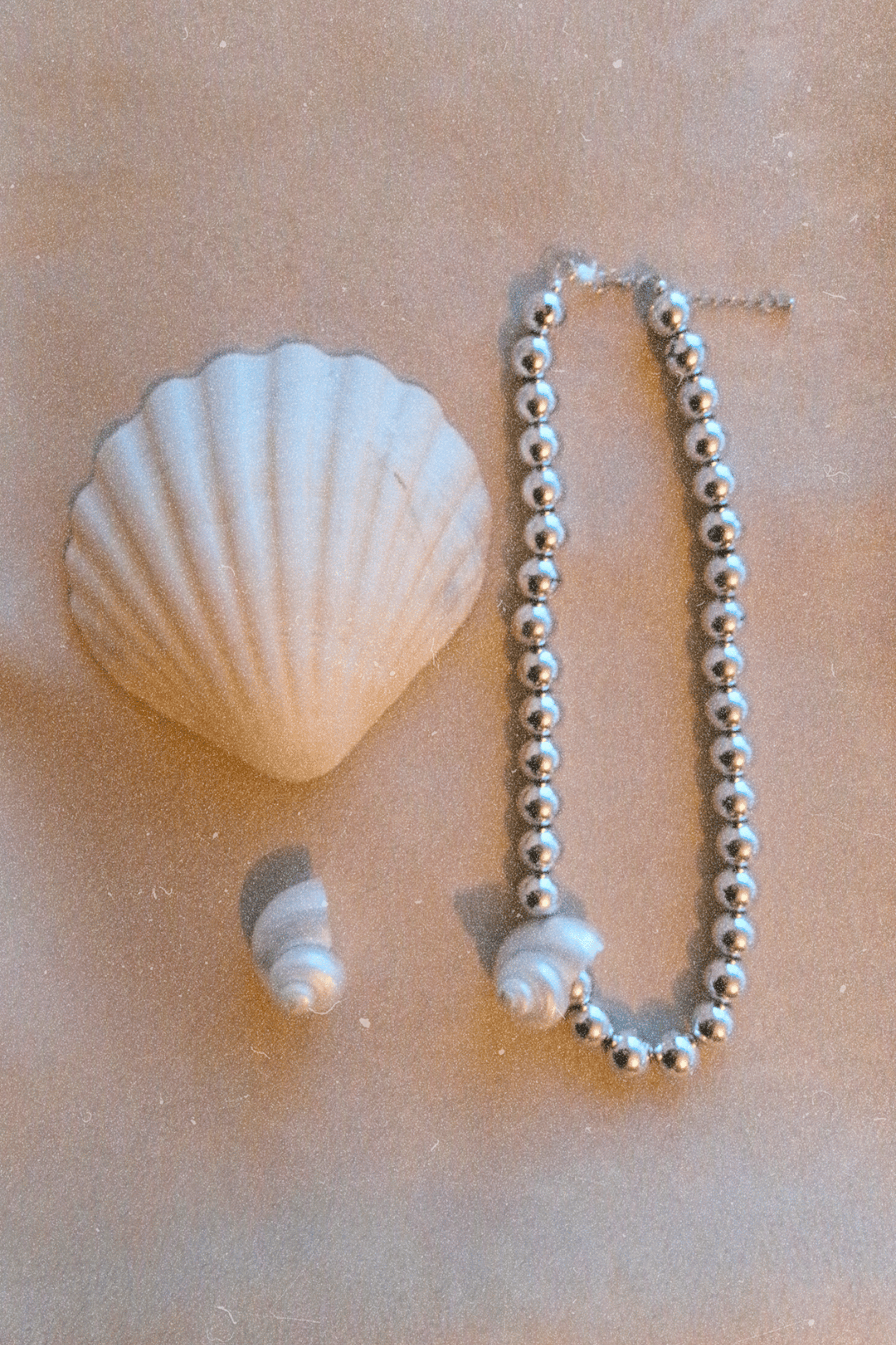 Shell and pearl necklace on a beige surface